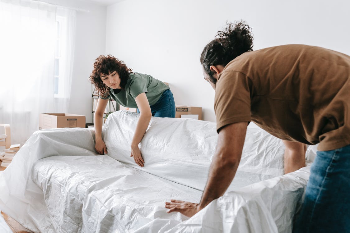 A man and a woman relocating a couch before long-distance moving
